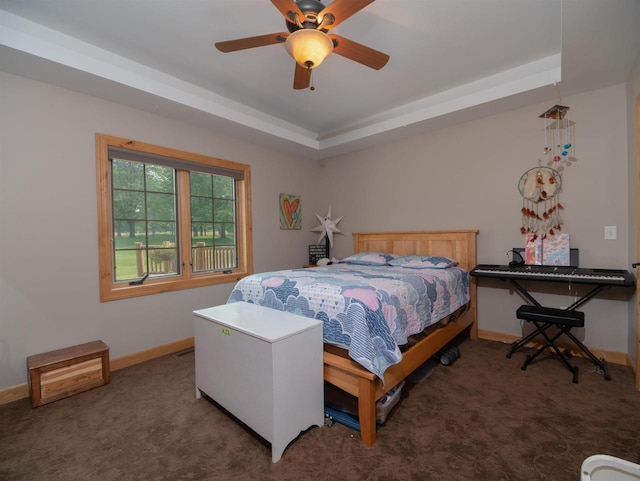 bedroom with dark carpet, a raised ceiling, and ceiling fan