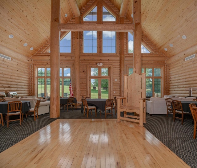 living room with high vaulted ceiling, rustic walls, wood ceiling, and light hardwood / wood-style flooring