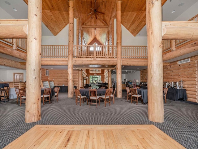 dining area featuring ornate columns, high vaulted ceiling, rustic walls, hardwood / wood-style flooring, and wooden ceiling