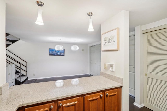 kitchen featuring light stone counters, dark hardwood / wood-style floors, and pendant lighting