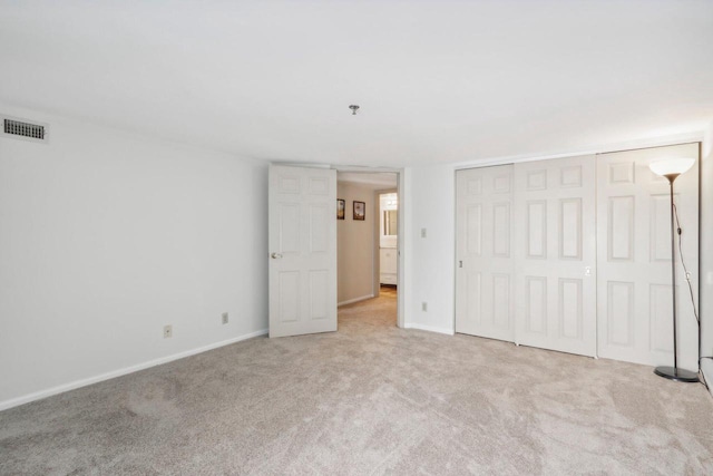 unfurnished bedroom with light carpet and a closet