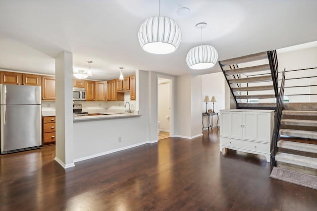 kitchen featuring wood-type flooring, stainless steel appliances, kitchen peninsula, and pendant lighting