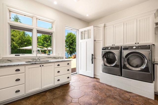 laundry area featuring sink, washer and clothes dryer, and cabinets