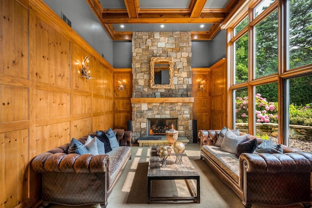 living room with a high ceiling, a stone fireplace, wooden walls, and beam ceiling