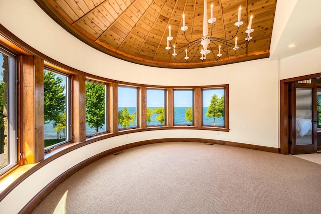 unfurnished room with carpet flooring, wood ceiling, a chandelier, and a tray ceiling