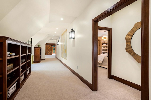 hallway with lofted ceiling and light colored carpet