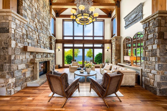 living room with hardwood / wood-style floors, a fireplace, a high ceiling, a notable chandelier, and beam ceiling