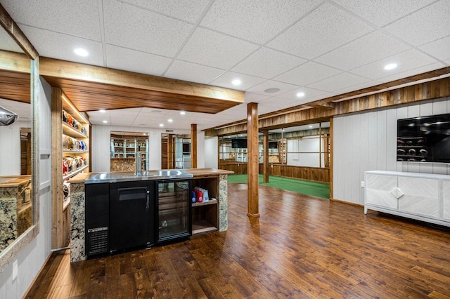 bar featuring wine cooler, dark hardwood / wood-style flooring, and wood walls