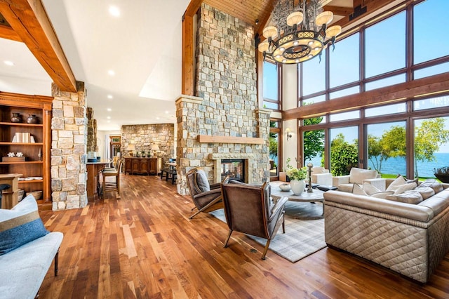 living room with a chandelier, a fireplace, beamed ceiling, and wood-type flooring