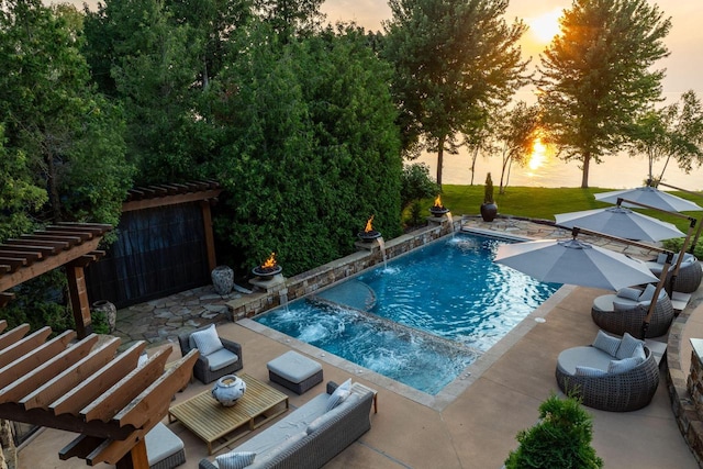 pool at dusk with a patio and pool water feature