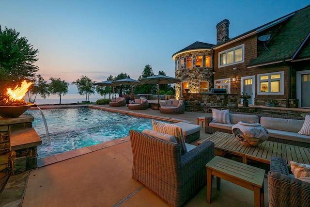 pool at dusk featuring an outdoor living space and pool water feature