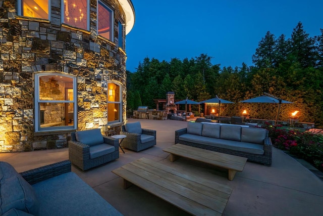 patio terrace at dusk featuring an outdoor living space with a fireplace