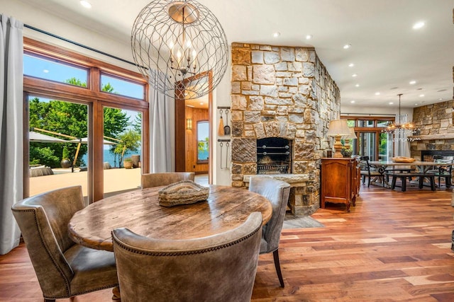 dining room with an inviting chandelier, a fireplace, and hardwood / wood-style floors