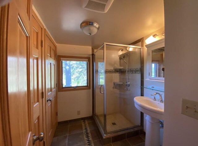 bathroom with a shower with shower door, tile patterned floors, and sink