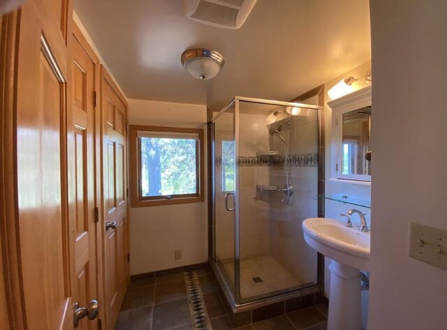 bathroom with an enclosed shower and tile patterned floors