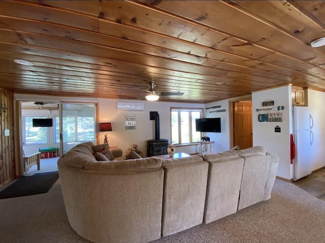 living room with wood ceiling, carpet floors, and a wood stove