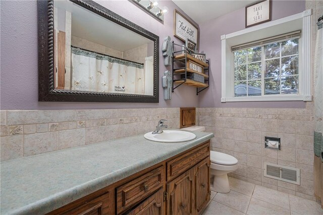 bathroom featuring tile patterned flooring, tile walls, toilet, and vanity