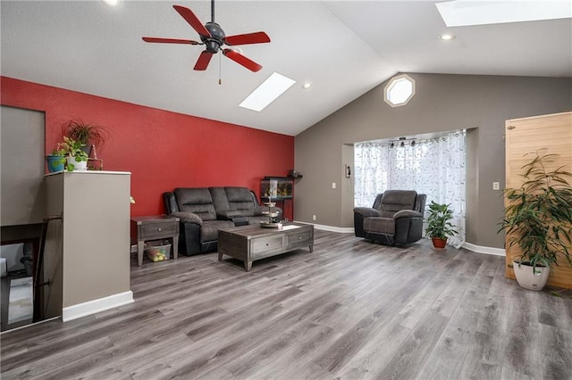 living room with lofted ceiling with skylight, ceiling fan, and wood-type flooring