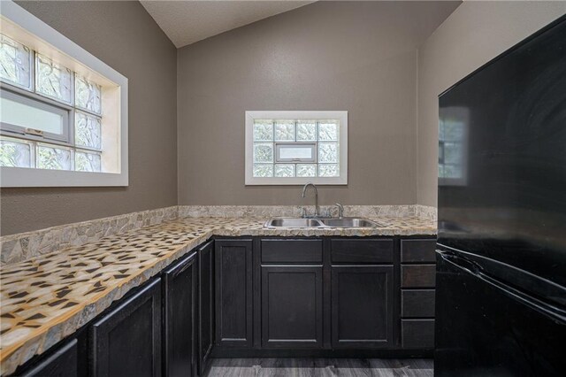 interior space with black fridge, hardwood / wood-style flooring, and sink