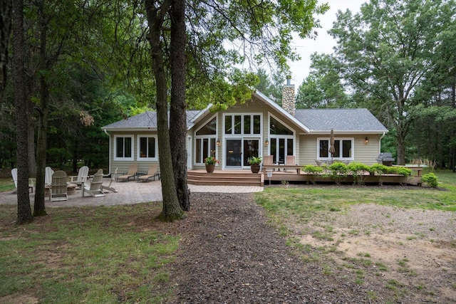 back of property with an outdoor fire pit, a deck, and a patio