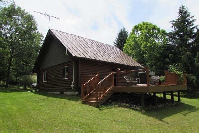 rear view of property featuring a wooden deck and a lawn