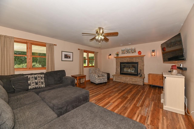 living room with ceiling fan, dark hardwood / wood-style floors, and a stone fireplace