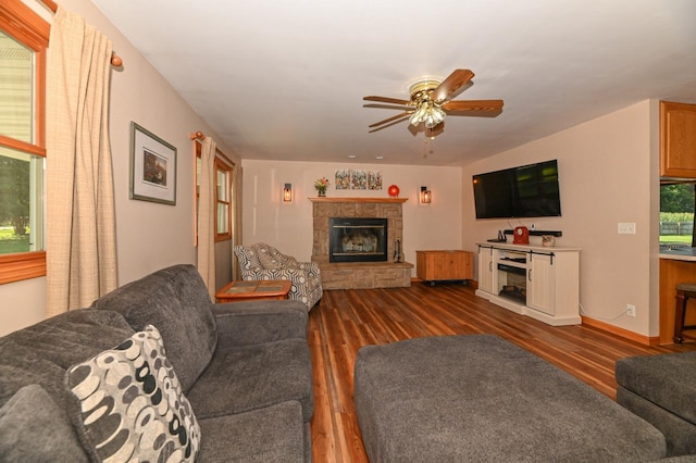 living room featuring a wealth of natural light, dark wood-type flooring, ceiling fan, and a fireplace