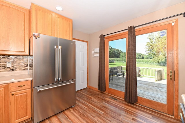 kitchen featuring a wealth of natural light, high end refrigerator, decorative backsplash, and light hardwood / wood-style floors