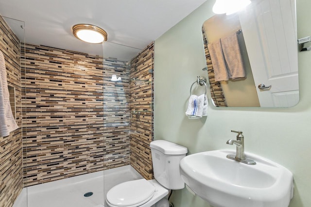 bathroom with toilet, sink, and a tile shower