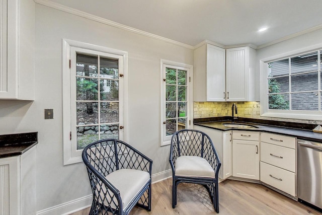 kitchen with dishwasher, white cabinetry, ornamental molding, light hardwood / wood-style flooring, and sink