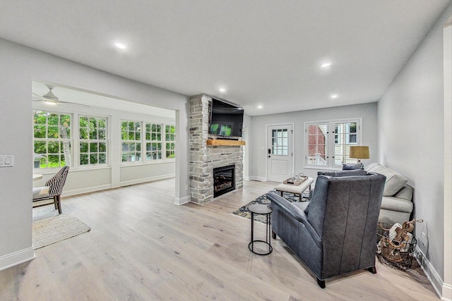 living room with ceiling fan, a fireplace, and light hardwood / wood-style flooring