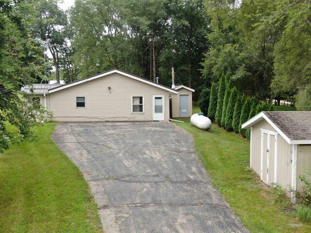 view of front of property featuring a front lawn and a storage shed