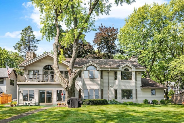 rear view of house featuring a balcony and a yard