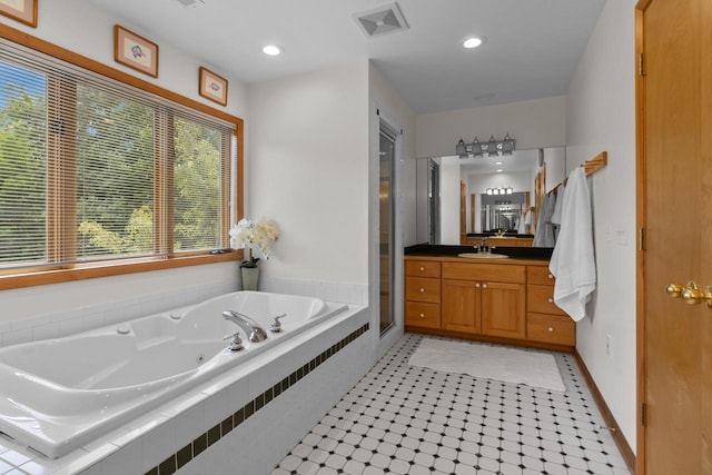 bathroom with vanity, a relaxing tiled tub, and tile patterned flooring