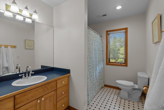 bathroom with toilet, vanity, and tile patterned flooring