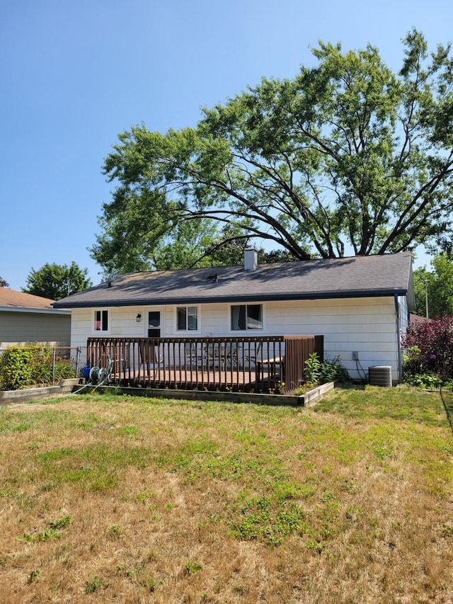 view of front of property with a front lawn, a wooden deck, and central AC