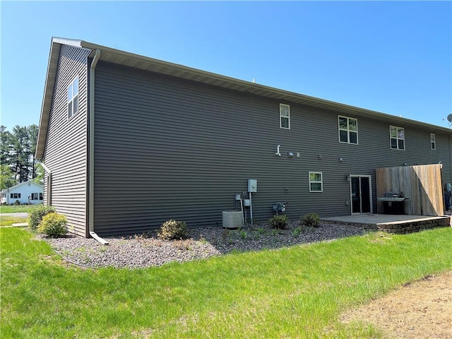 rear view of house with a patio, central air condition unit, and a lawn