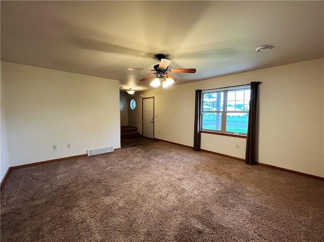 empty room featuring ceiling fan and dark colored carpet