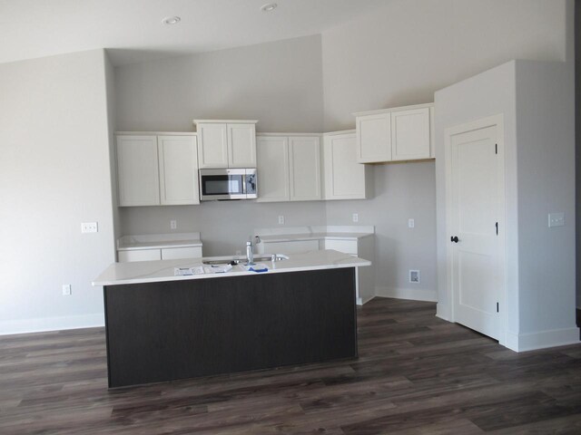 518 Woodside Ct, West Bend, WI 53095 - kitchen featuring a center island, white cabinets, a towering ceiling, stainless steel microwave, and baseboards