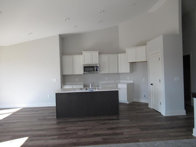 518 Woodside Ct, West Bend, WI 53095 - kitchen featuring stainless steel microwave, baseboards, white cabinetry, and a towering ceiling