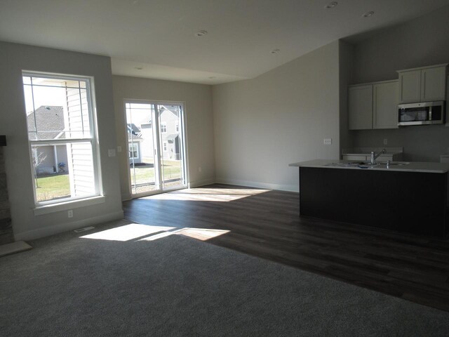518 Woodside Ct, West Bend, WI 53095 - unfurnished living room featuring dark wood-style floors, dark colored carpet, baseboards, and a sink