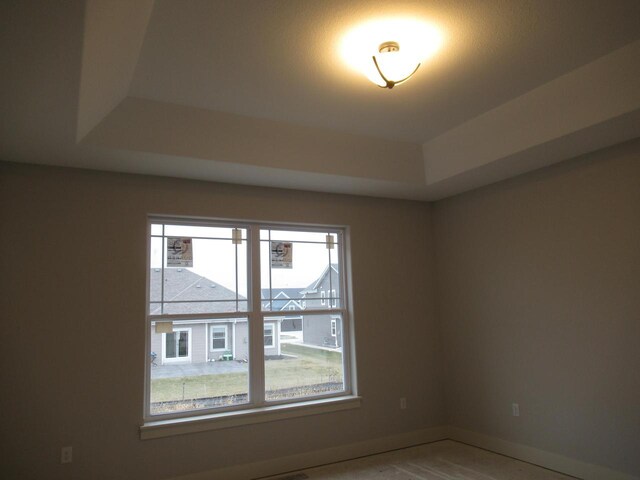 518 Woodside Ct, West Bend, WI 53095 - unfurnished room featuring a raised ceiling, a healthy amount of sunlight, and baseboards