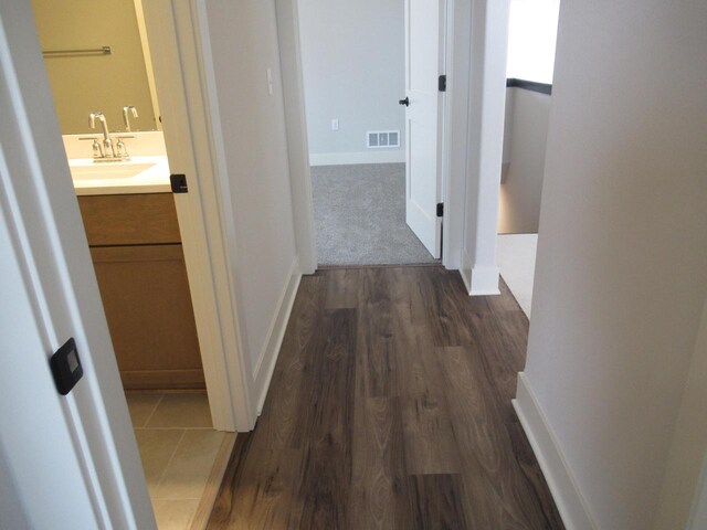 518 Woodside Ct, West Bend, WI 53095 - hallway featuring baseboards, visible vents, a sink, and dark wood-type flooring