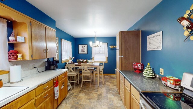 kitchen featuring pendant lighting, rail lighting, sink, tasteful backsplash, and a chandelier