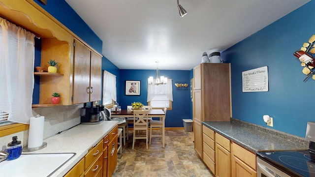 kitchen featuring a notable chandelier, stainless steel electric range, sink, and hanging light fixtures