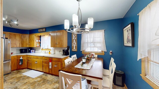 kitchen with stainless steel refrigerator, decorative backsplash, sink, and a notable chandelier