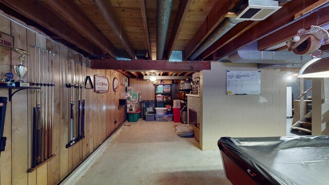 basement featuring brick wall, wooden walls, white refrigerator, a fireplace, and pool table