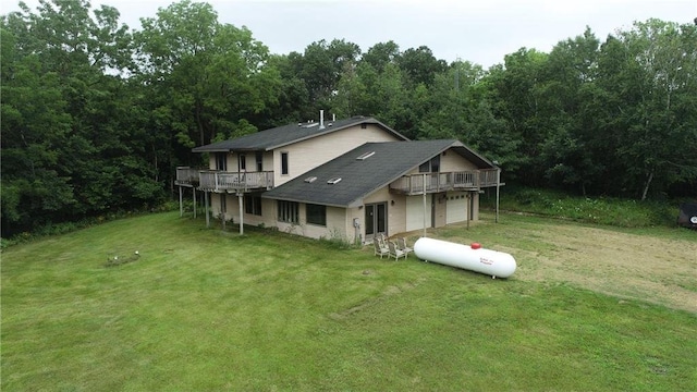 back of property with a wooden deck, a garage, and a lawn