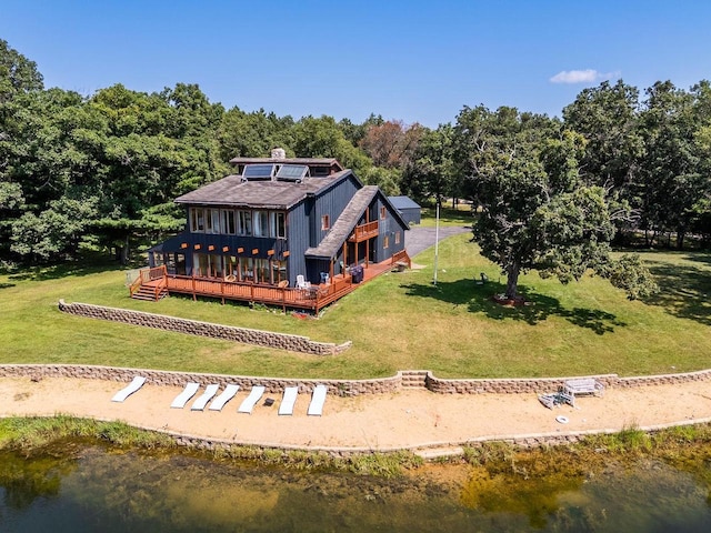 rear view of house featuring a deck with water view and a yard