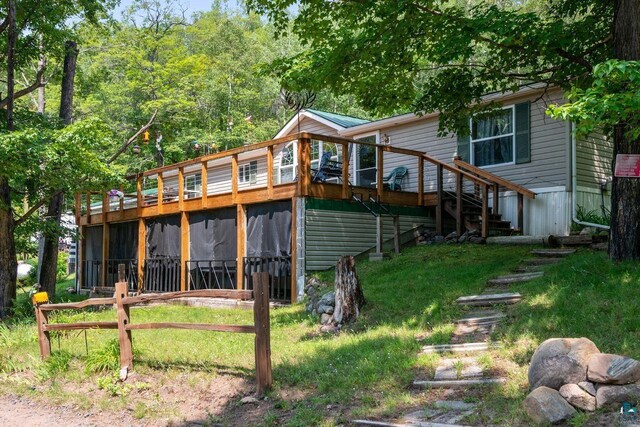 rear view of property featuring a wooden deck and a lawn